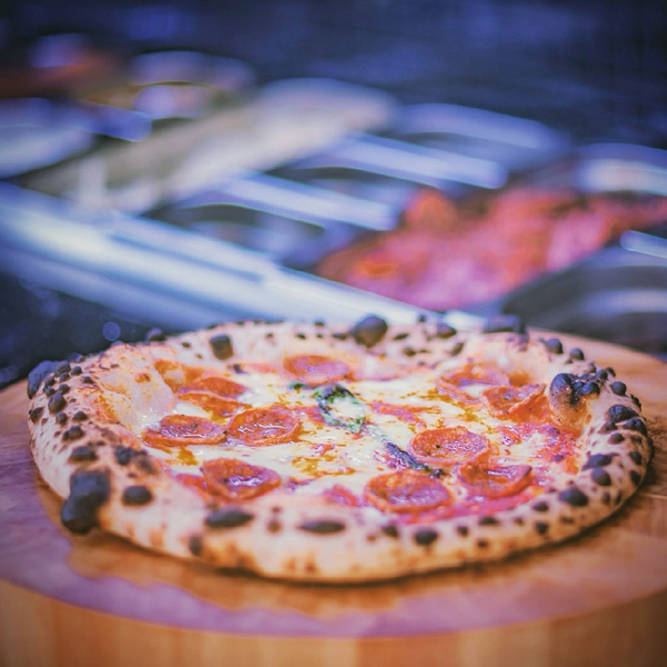 A pepperoni pizza on a wooden board, with a crispy crust fresh from the oven